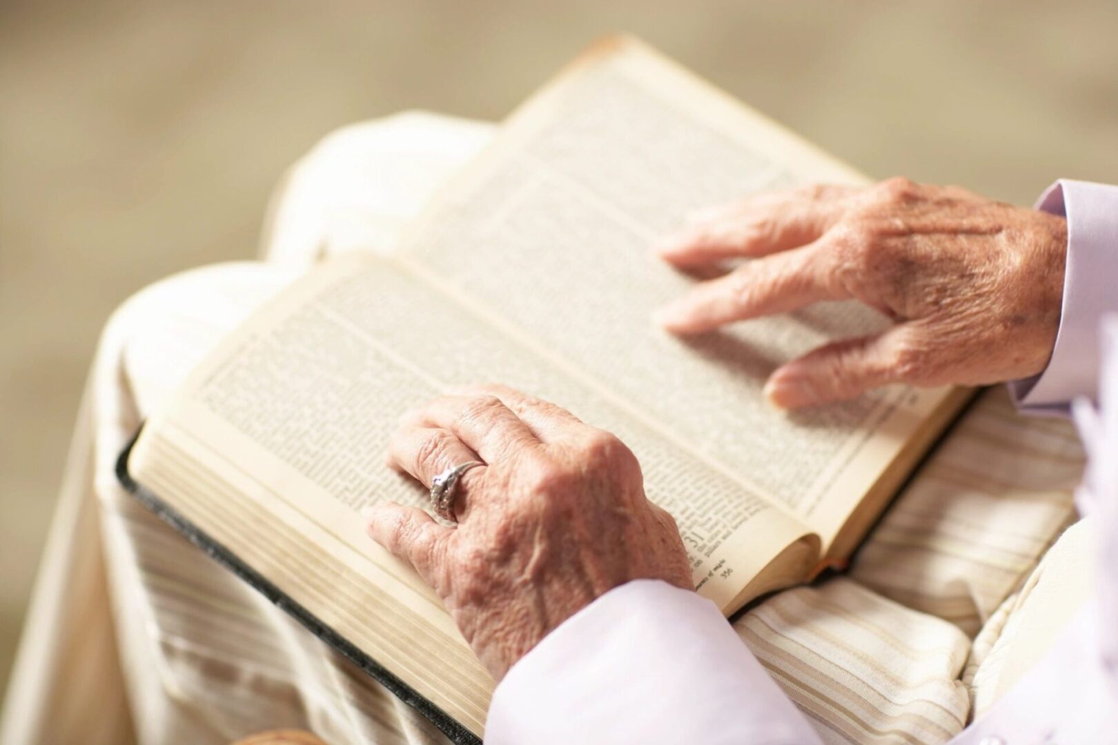 Elderly person reading an open book with focus on hands. Elderly person reading an open book with focus on hands.