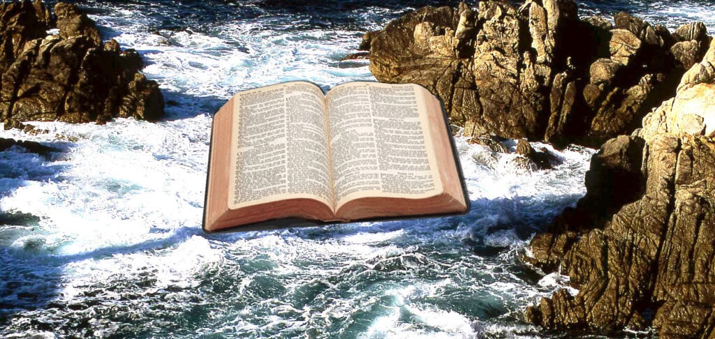 Opened Bible floating over troubled water crashing against rocky cliffs