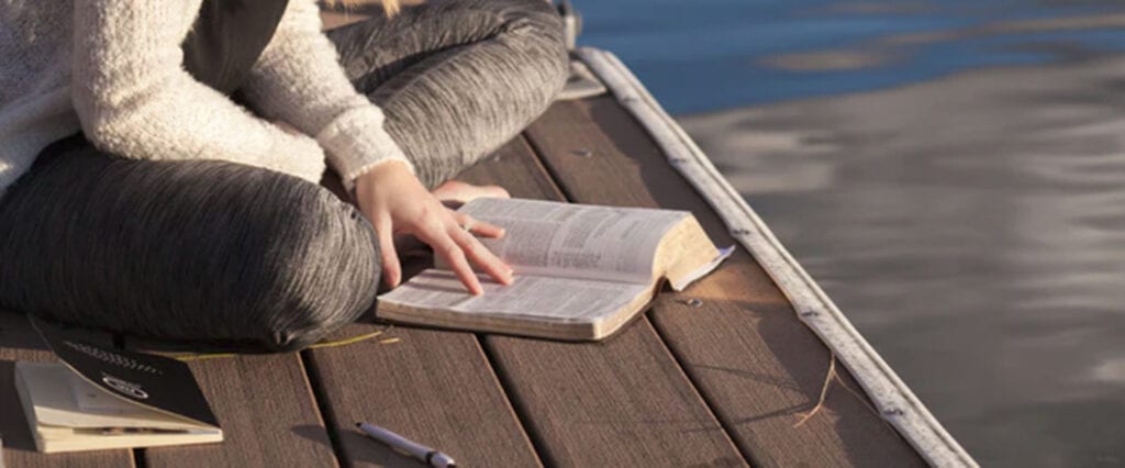 Woman reading the Bible on a dock