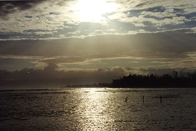 Sunset over a calm sea with silhouetted land and clouds. Sunset over a calm sea with silhouetted land and clouds.
