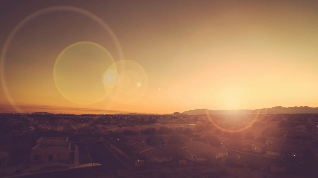 Sunset over a serene desert landscape with sun flare.