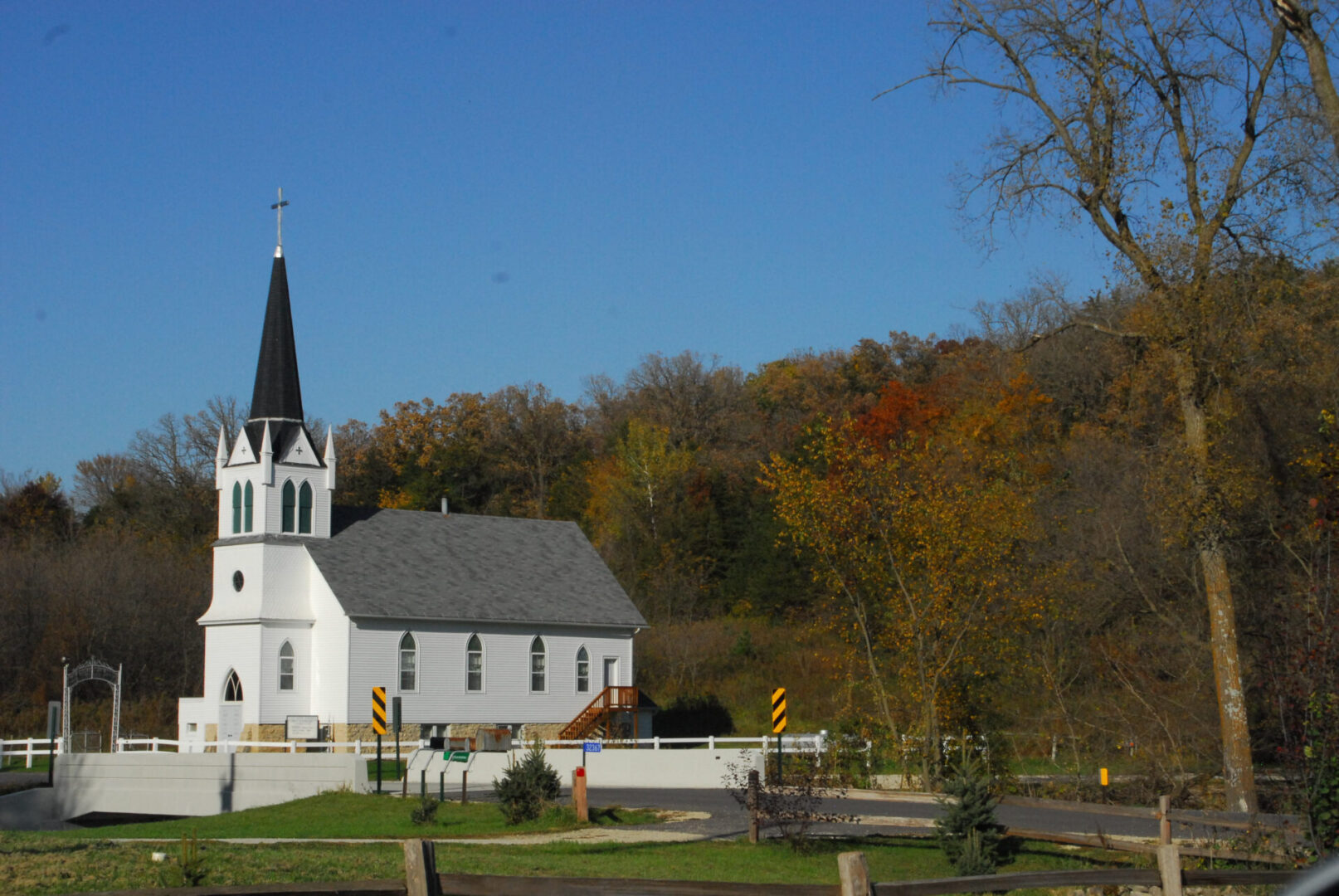White church with a tall steeple surrounded by autumn trees. White church with a tall steeple surrounded by autumn trees.