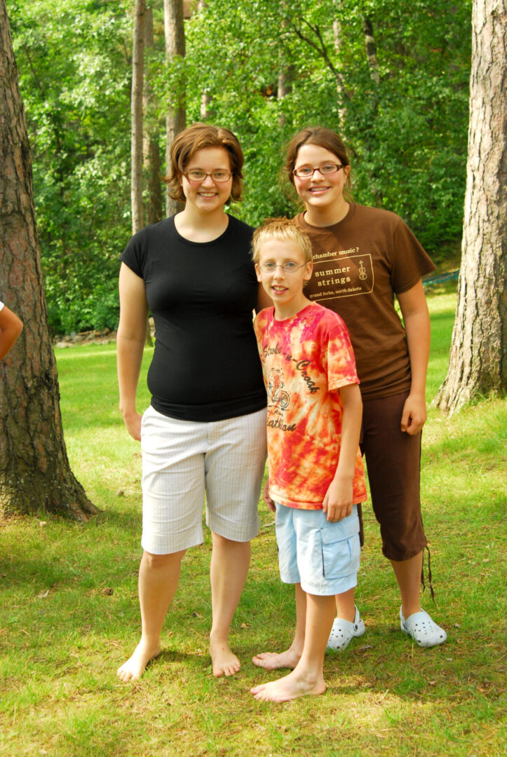 Three smiling girls standing outdoors near trees. Three smiling girls standing outdoors near trees.