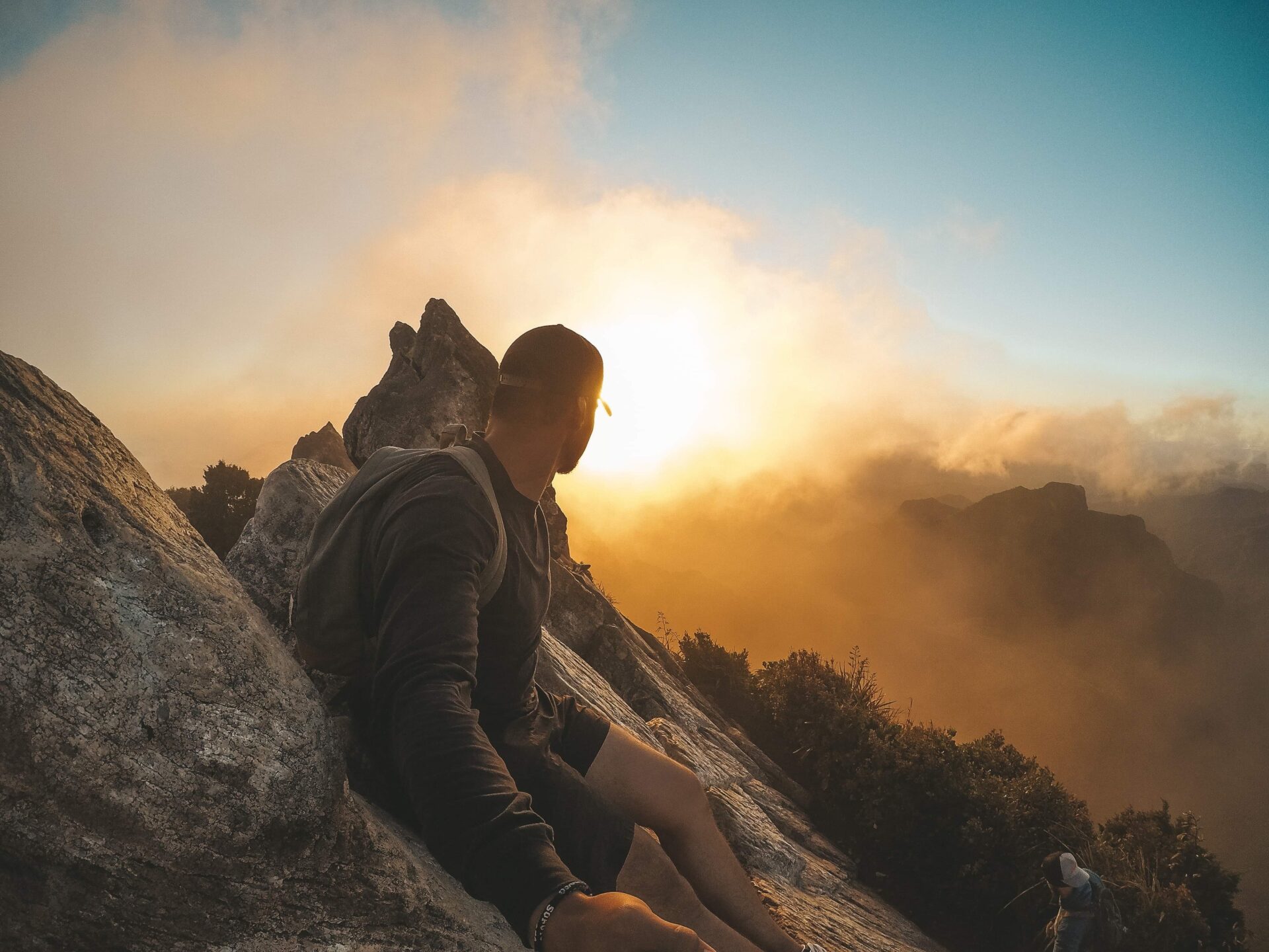 Person sitting on rocky terrain during a misty sunrise or sunset. Person sitting on rocky terrain during a misty sunrise or sunset.
