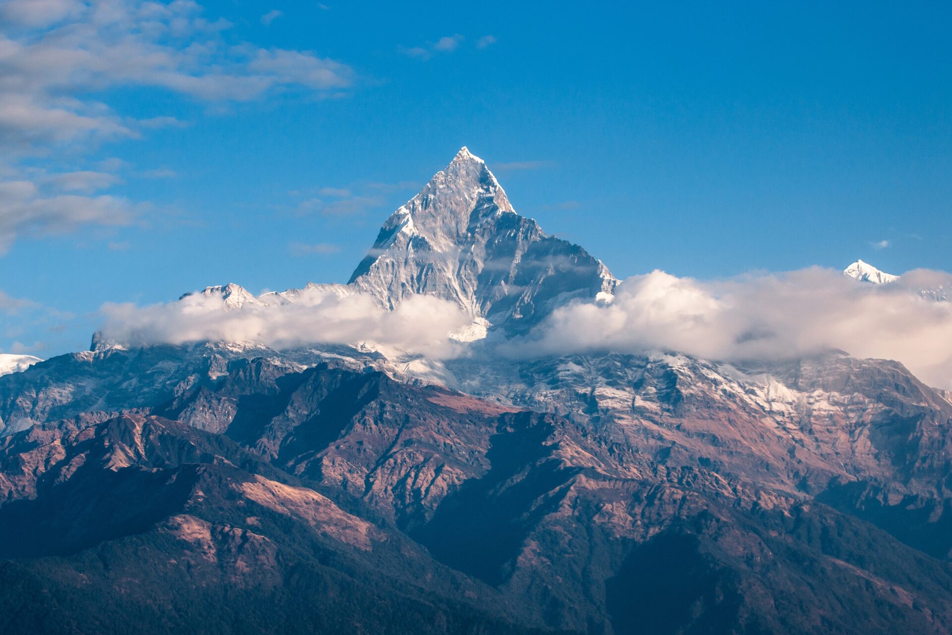 Snow-capped mountain peak rising above clouds under a clear blue sky. Snow-capped mountain peak rising above clouds under a clear blue sky.