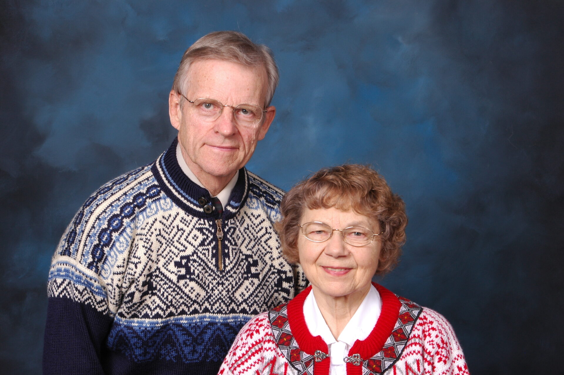 An elderly couple smiling in front of a blue backdrop. An elderly couple smiling in front of a blue backdrop.