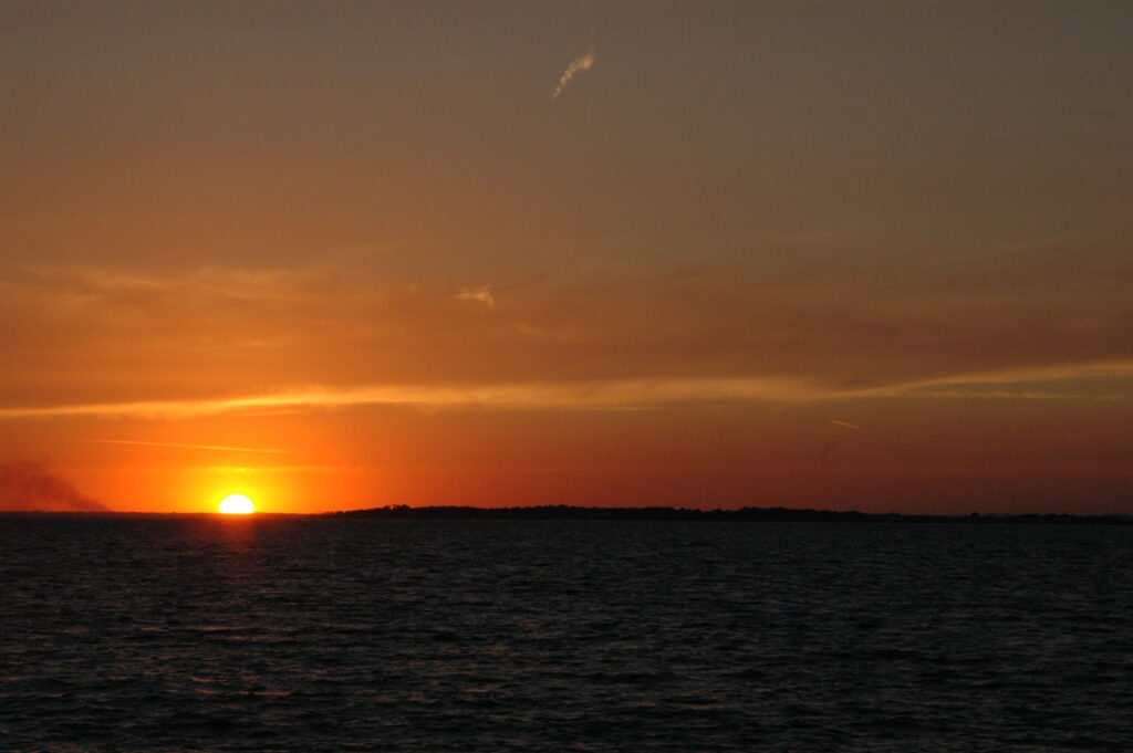Sunset over calm ocean waters with a clear sky.