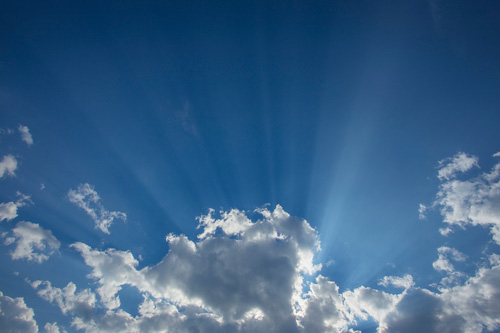 Sun rays shining through clouds in a clear blue sky. Sun rays shining through clouds in a clear blue sky.