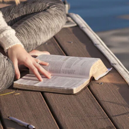 Woman reading the Bible on a dock